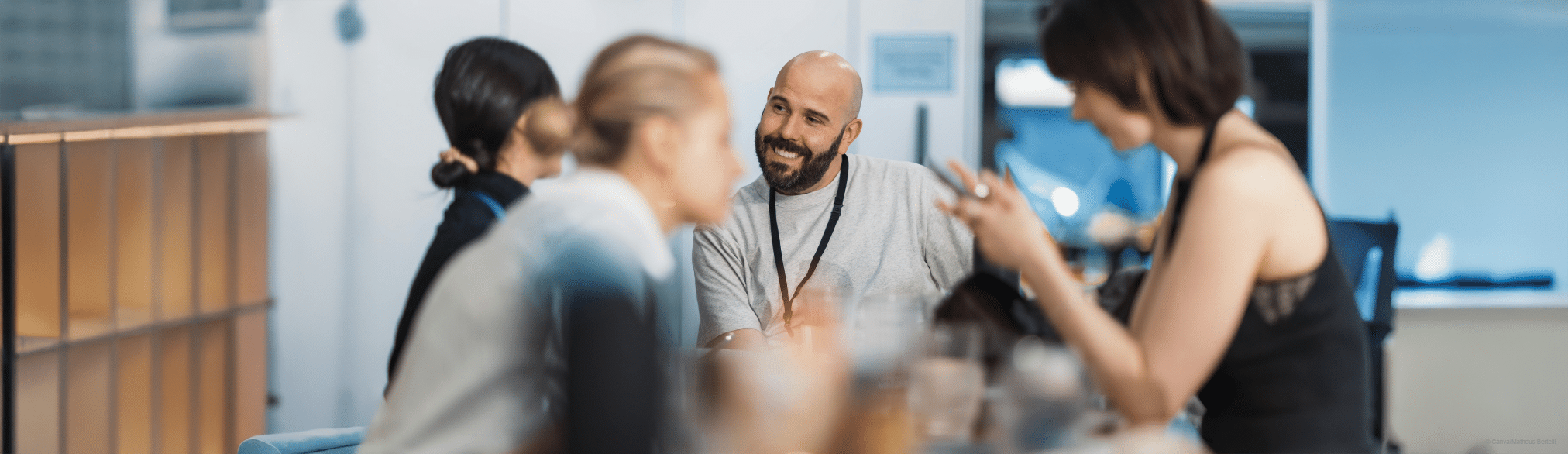 © Canva/Matheus Bertelli Vier Personen, die sich in einem Büro unterhalten.